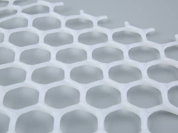 A piece of white hexagonal poultry bed netting on the floor.