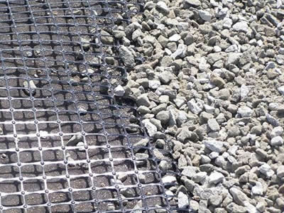 A piece of biaxial geogrid on the base and several gravels on it.