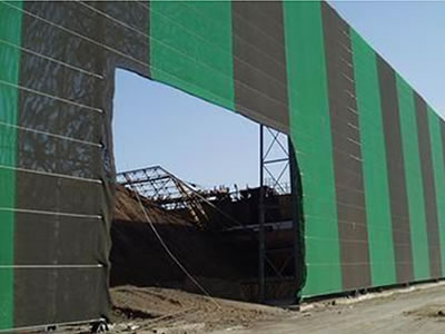 Green and black color flexible windbreak netting is installed surrounding the coal mine yard.