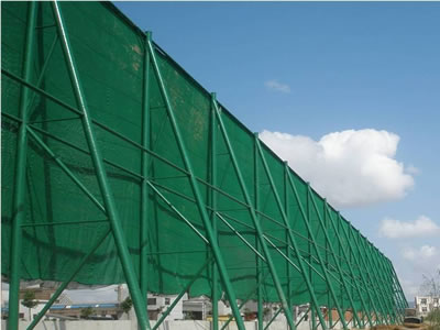 The green color flexible windbreak netting is installed beside of the river bank.
