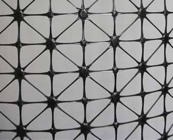 A piece of quaxial plastic geogrid on the gray background.