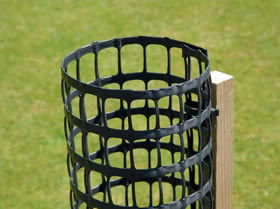 A piece of rectangular tree guard is fixed on a wooden post.